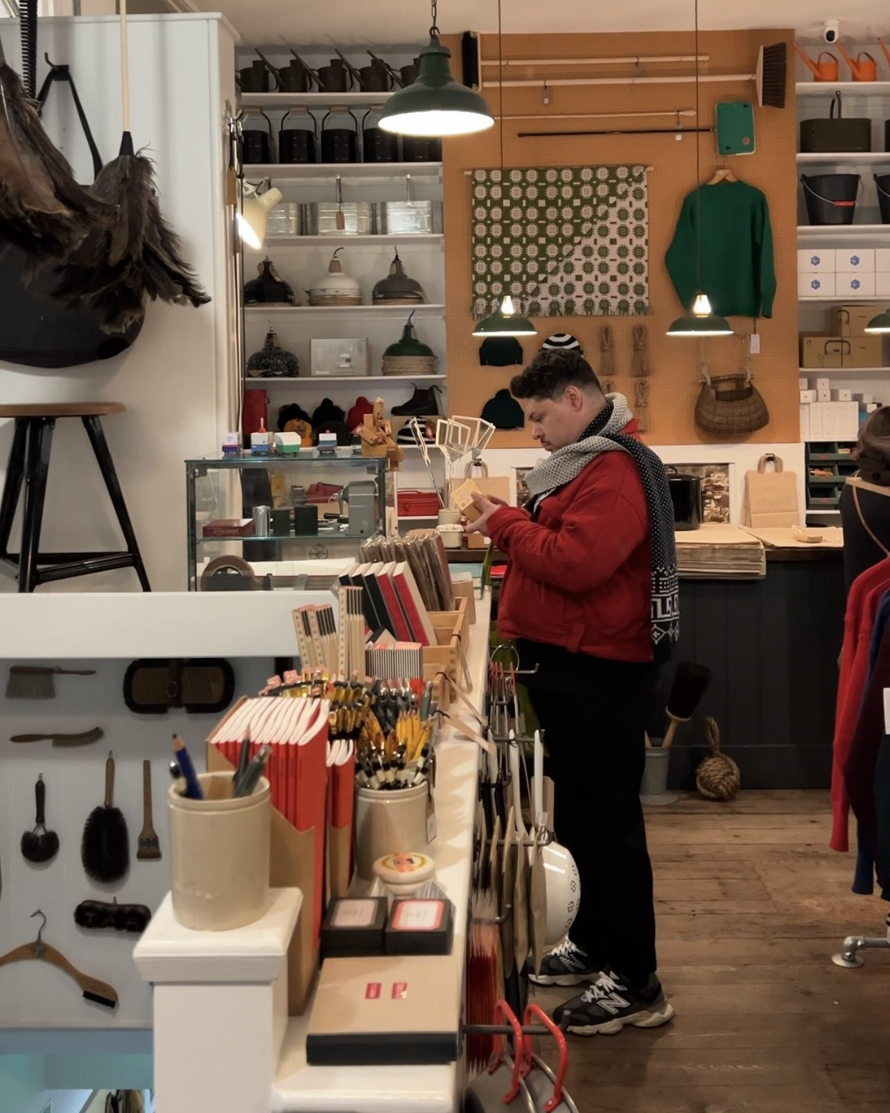 Pessoa observando produtos em loja de artigos de decoração, com objetos variados nas prateleiras.