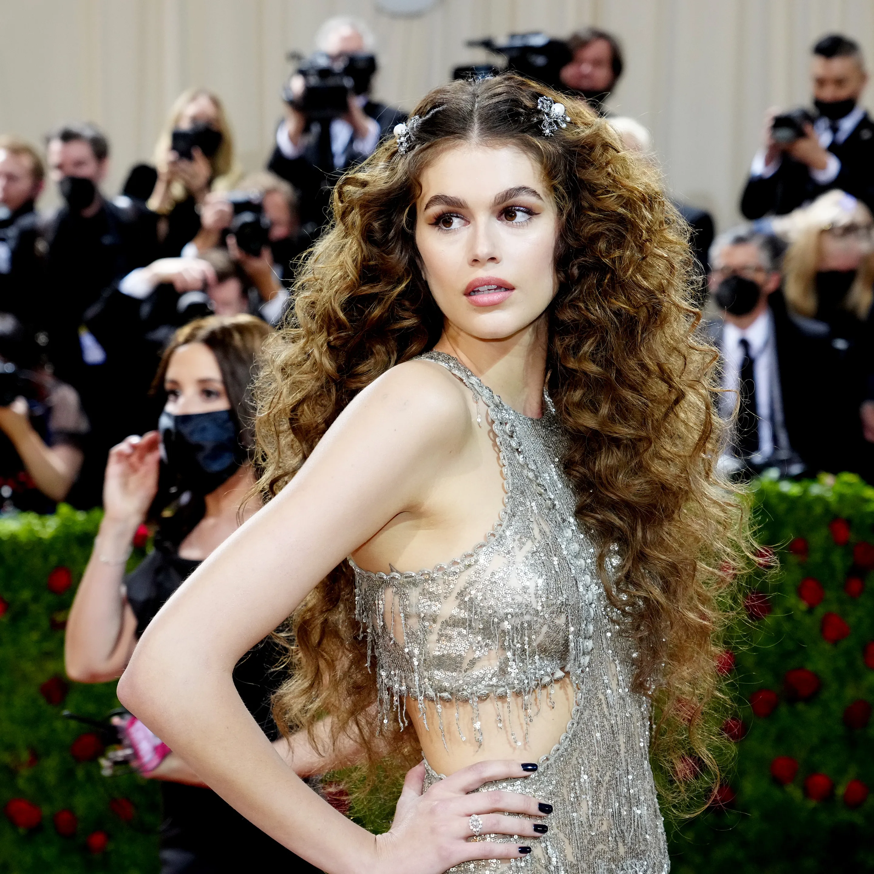 Jovem com cabelo cacheado volumoso e adornos prateados. Inspirador para penteados de madrinha de casamento.