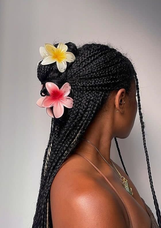 Tranças adornadas com flores coloridas, acessório da moda de 2025, em cabelo feminino.