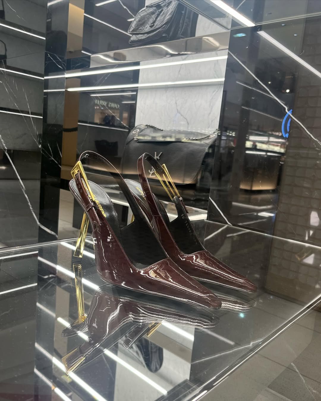 Sapatos de salto alto em verniz marrom com detalhes dourados em prateleira de loja elegante. Resoluções de estilo