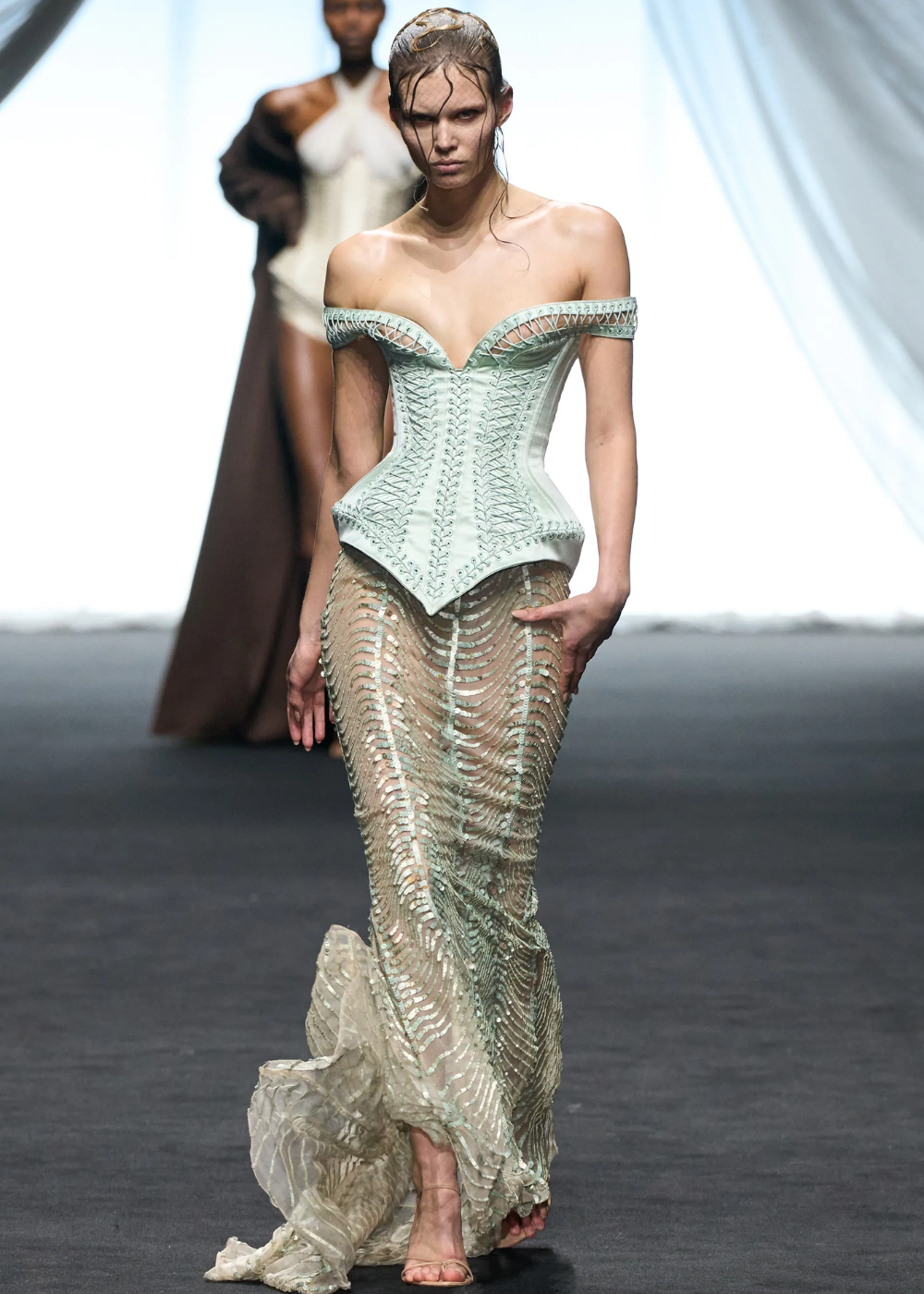 Modelo desfila com corset verde e saia transparente ornamentada na Semana de Alta-Costura 2025.