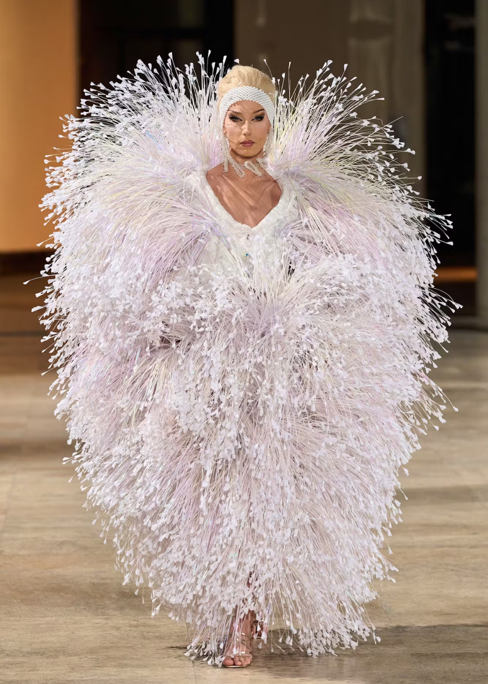 Modelo em um vestido extravagante com textura de plumas, destaque na Semana de Alta-Costura 2025.