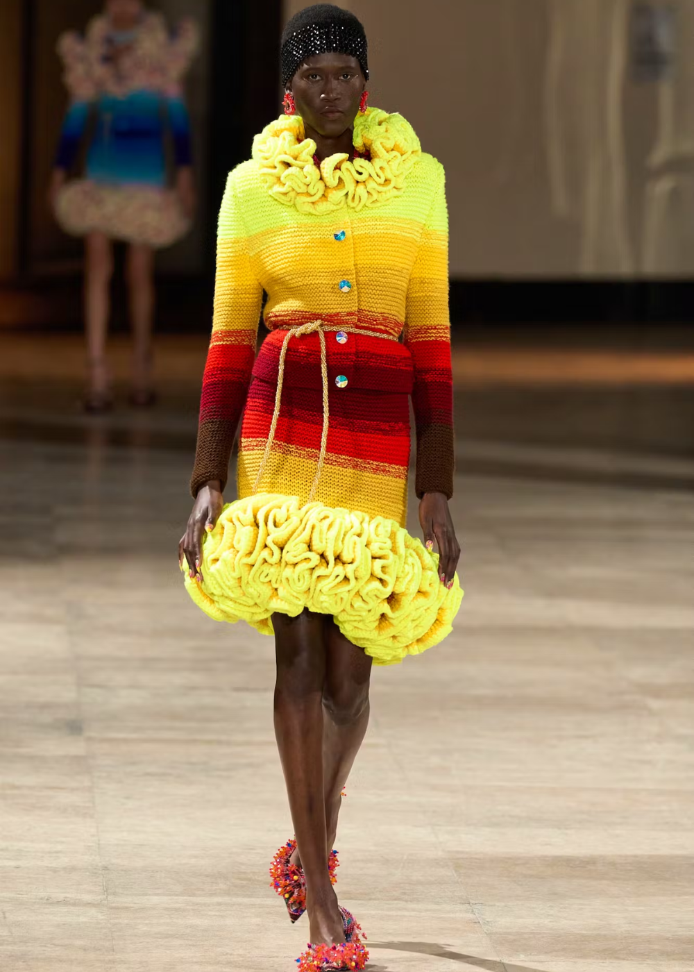 Modelo desfila com vestido colorido de crochê, com detalhes em vermelho e amarelo. Semana de Alta-Costura 2025.