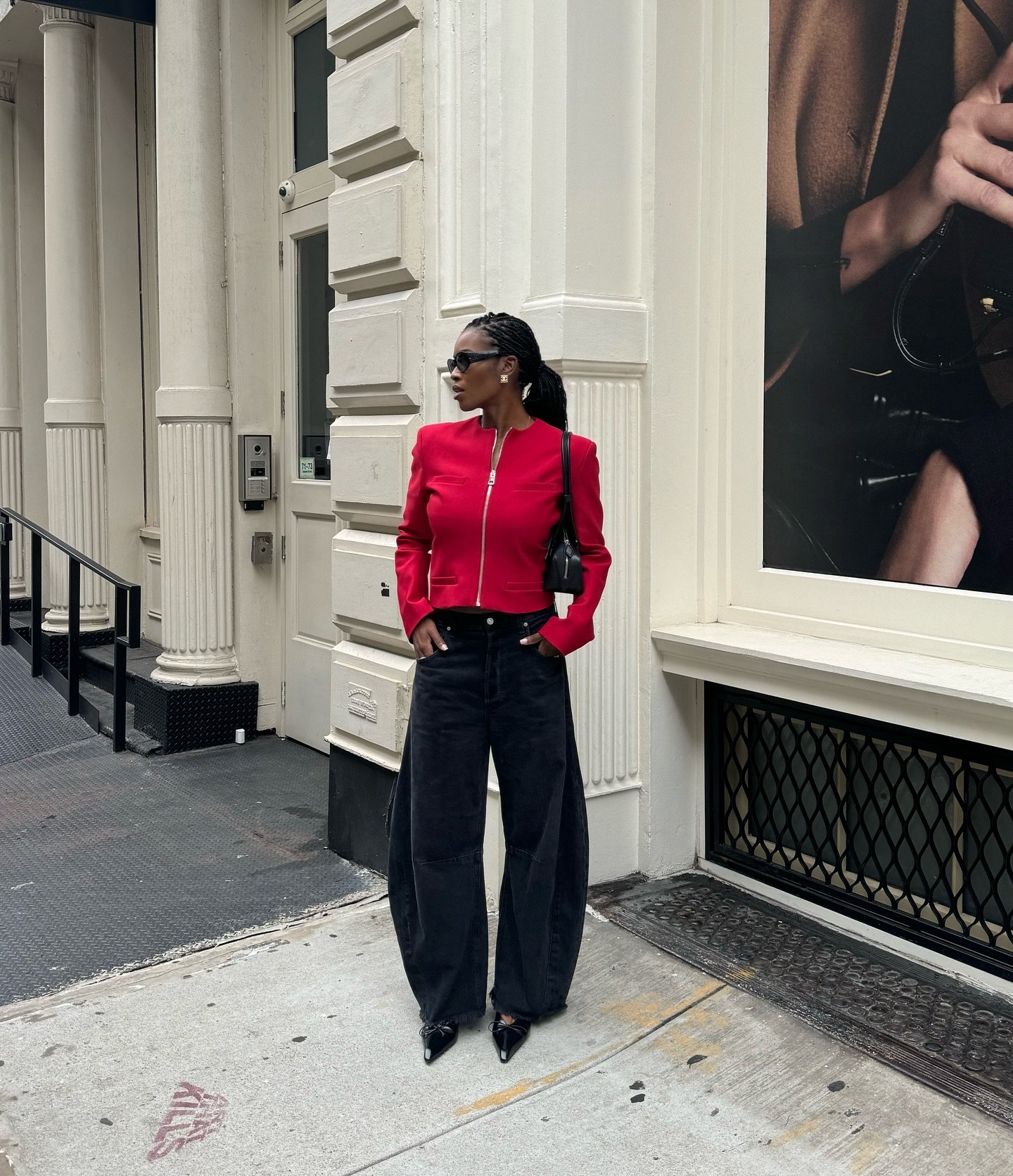 Mulher com penteado elegante, blazer vermelho e calças largas em rua urbana moderna. Tendências de moda urbana.