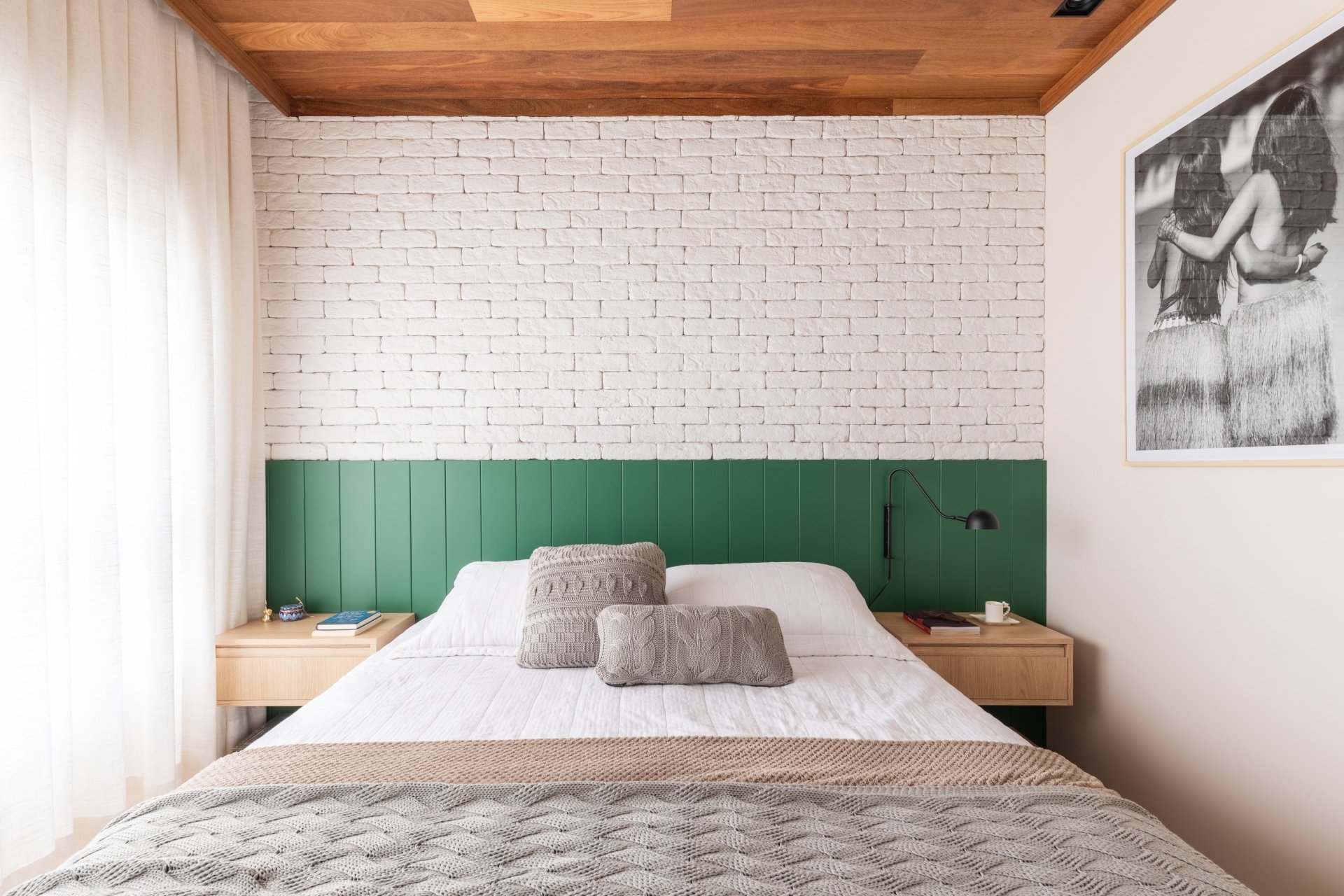 Cabeceira de cama com painel verde na decoração, almofadas de tricô e parede de tijolos brancos. Decor minimalista e aconchegante.