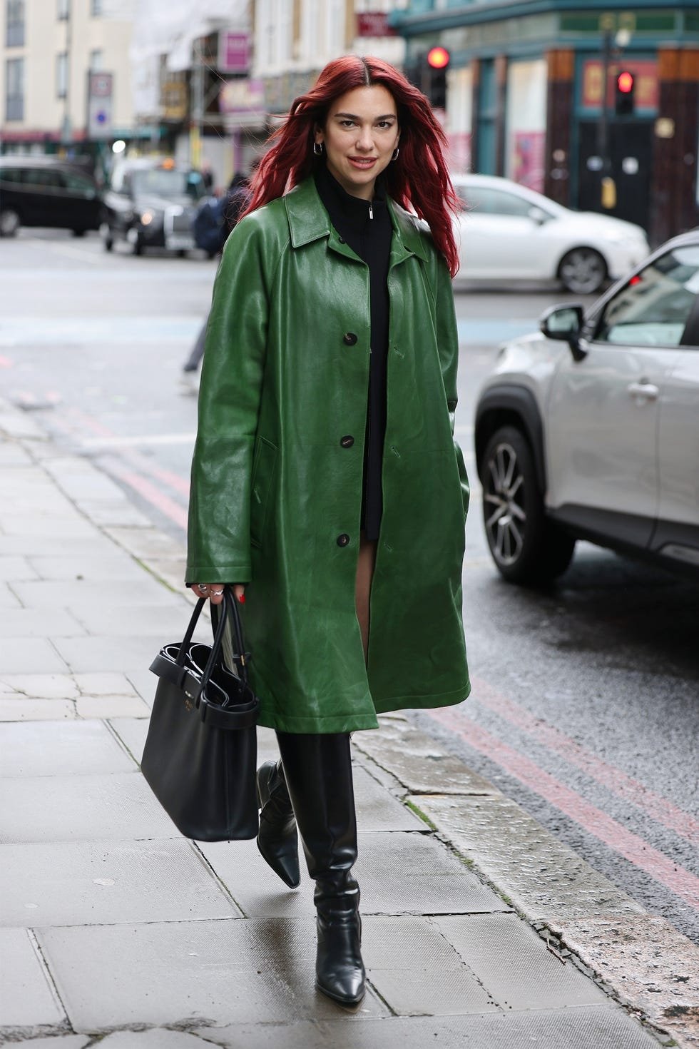 Pessoa com casaco verde e cabelo vermelho andando na calçada, simbolizando a moda de 2025.