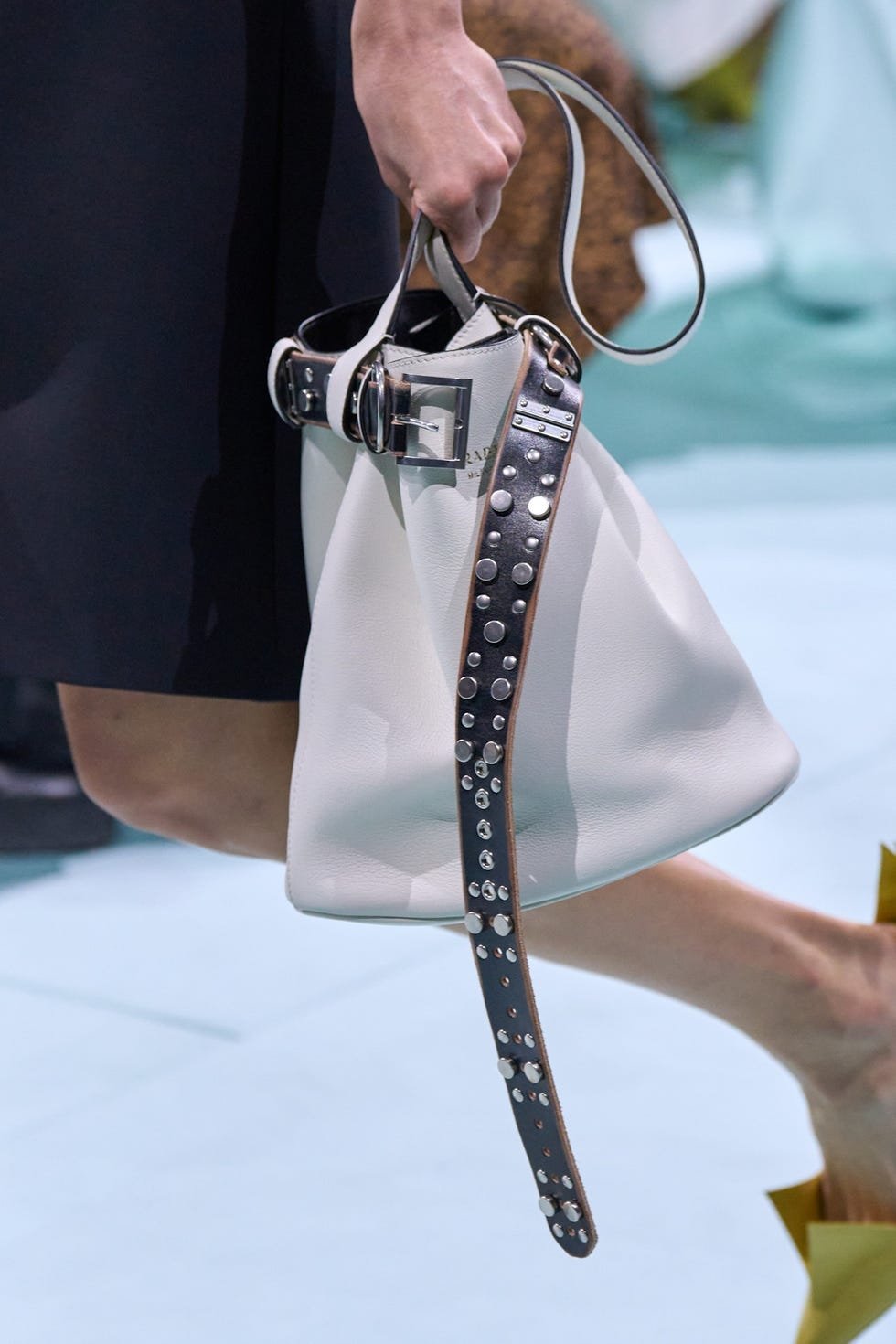 Bolsa moderna branca com detalhes metálicos e alça larga em destaque, tendência na moda de 2025.