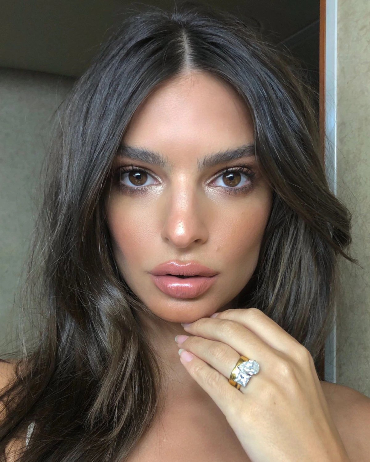 Mulher com cabelo escuro e liso exibe anel de noivado com grande diamante.