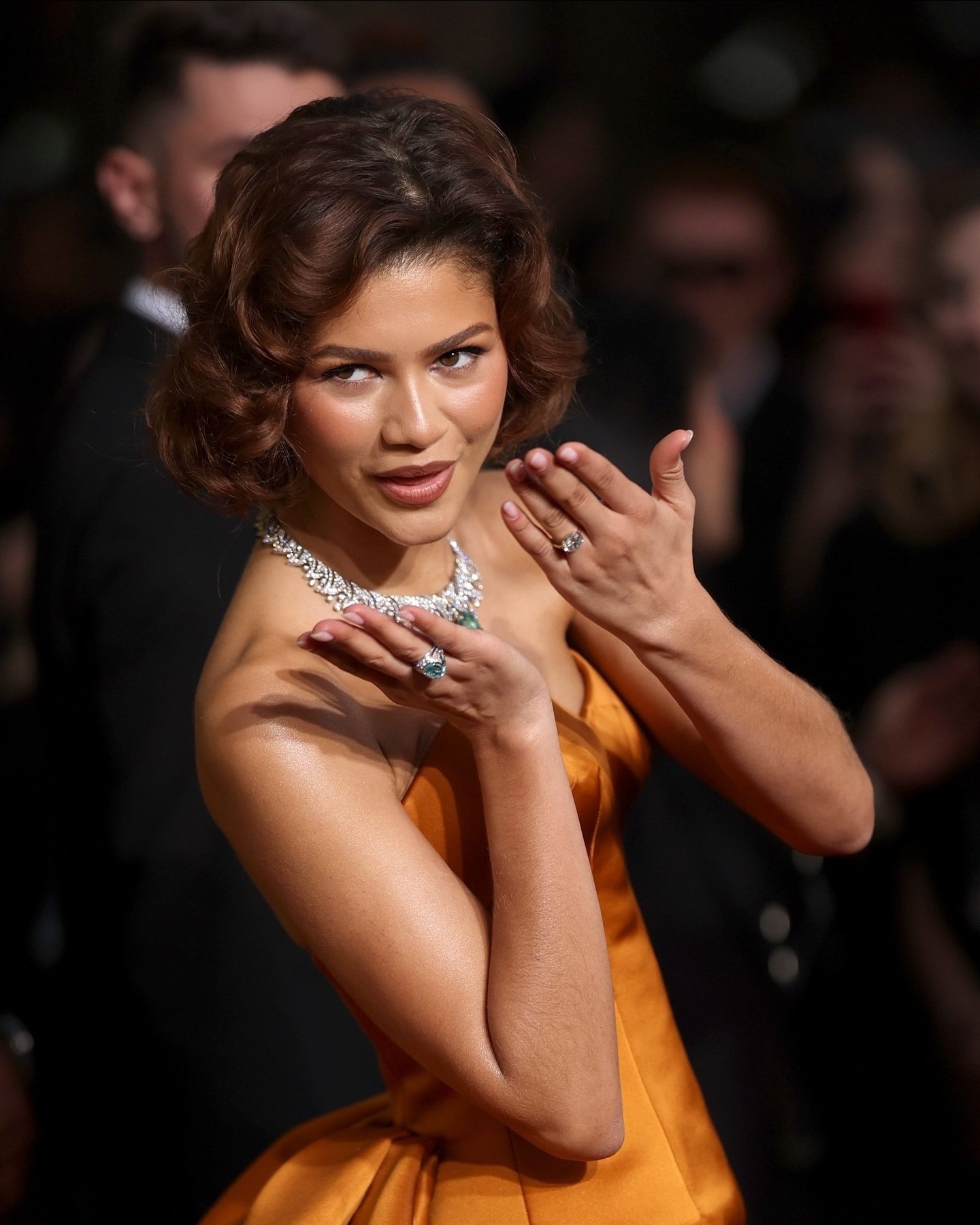 Celebridade em vestido glamouroso exibe elegante anel associado aos anéis de noivado famosos.