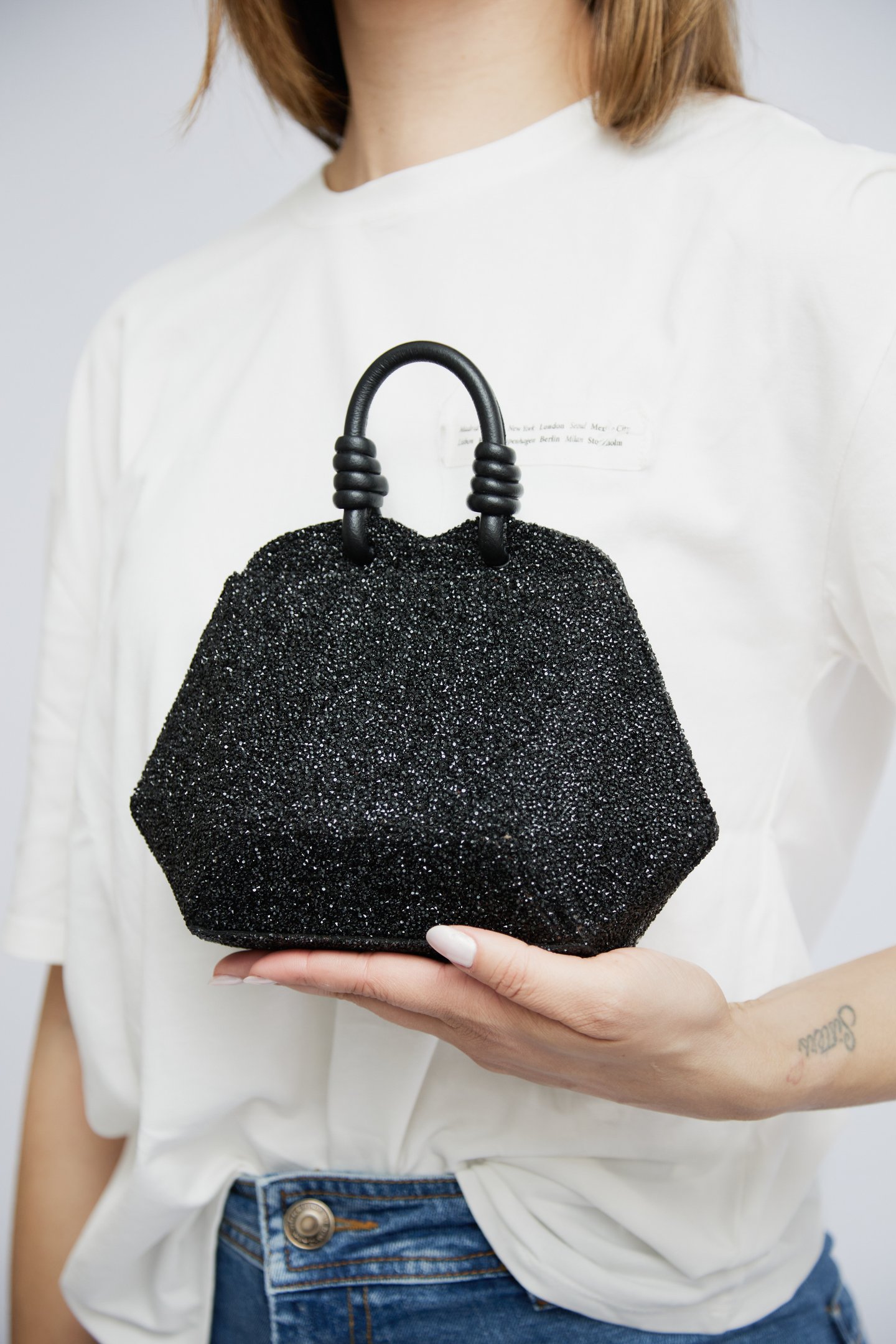 divulgação da campanha de lançamento da coleção Diamond Essence da marca Soleah. Na foto a modelo usa calça jeans, camiseta branca e segura a bolsa clutch diamond