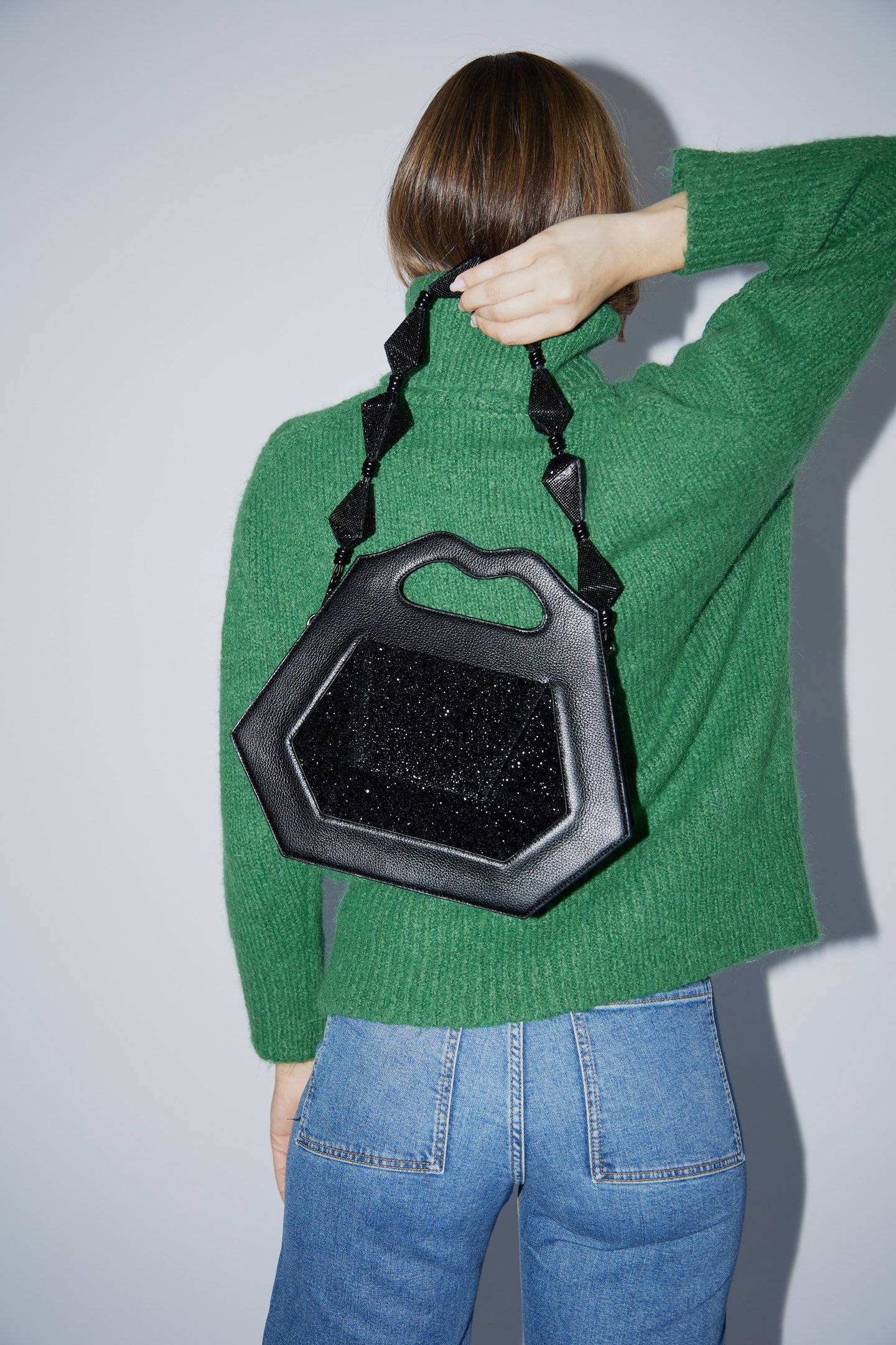 divulgação da campanha de lançamento da coleção Diamond Essence da marca Soleah. Na foto a modelo usa calça jeans, tricot verde e segura a bolsa clutch diamond