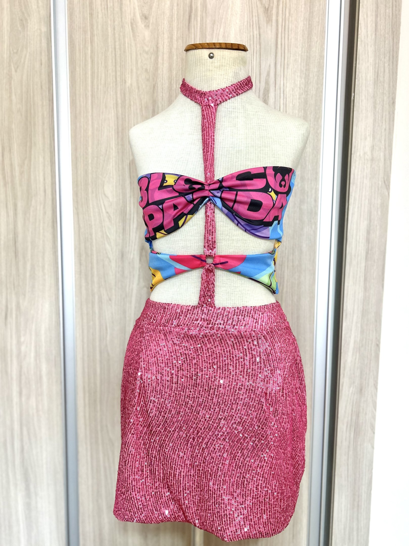 Manequim com top estampado colorido e saia rosa brilhante, ideal para customizar abadá.