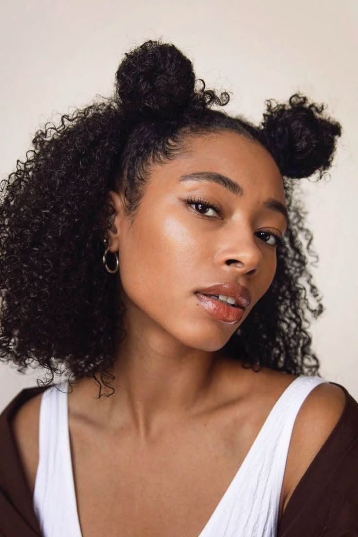 Mulher com penteado em coques pequenos e óculos de sol, usando blusa verde e preta. Dicas de cabelo