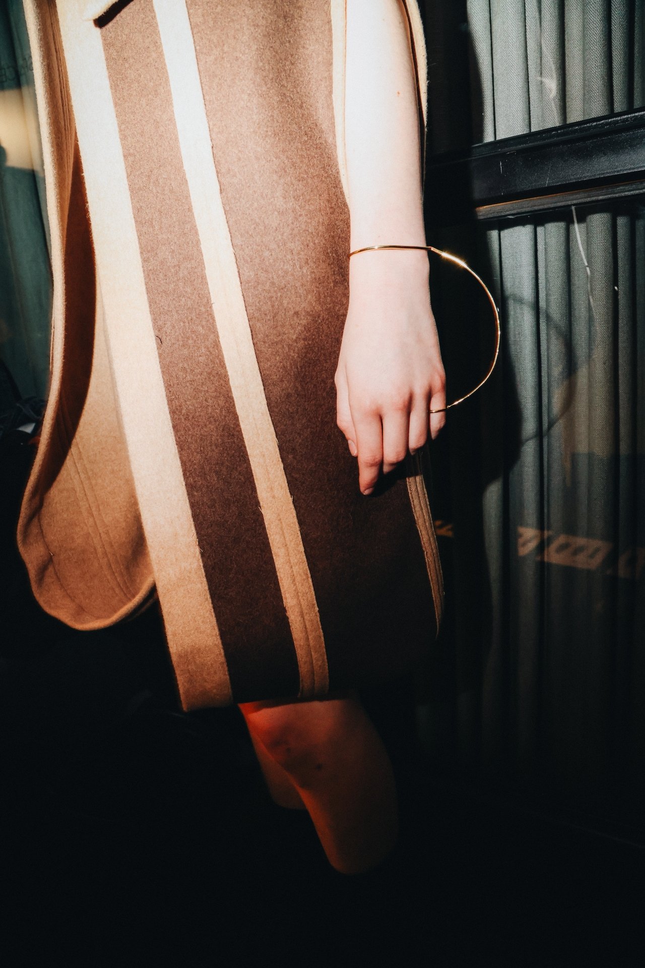 Roupa elegante com listras marrons e bege, complementada por uma pulseira Eleonora Hsiung dourada.