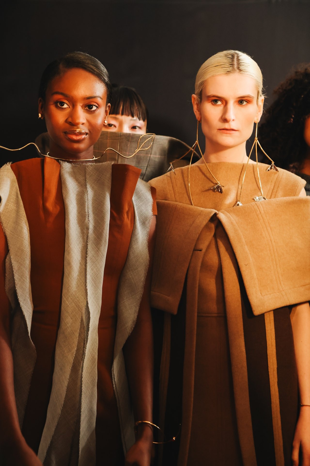 Modelos em roupas estruturadas com acessórios metálicos. Estilo marcante e contemporâneo, possivelmente inspirado por Eleonora Hsiung.