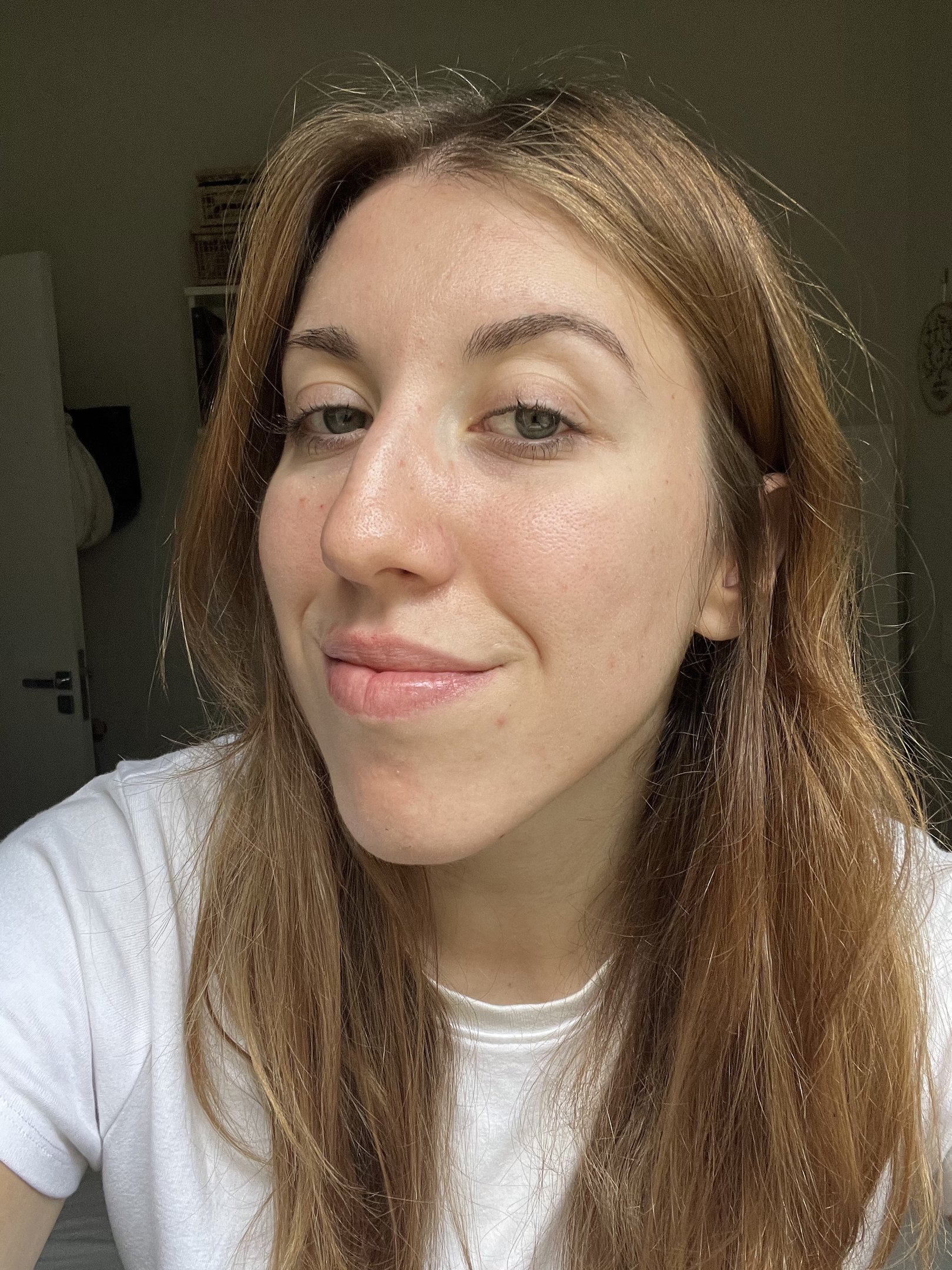 Pessoa sorrindo levemente em um ambiente interno, com destaque para os olhos ressaltando a importância dos cílios crescerem.