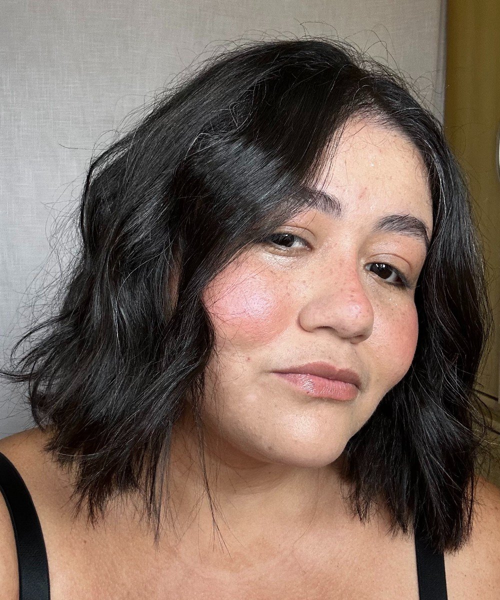 Mulher de cabelo escuro e curto com fios brancos visíveis.