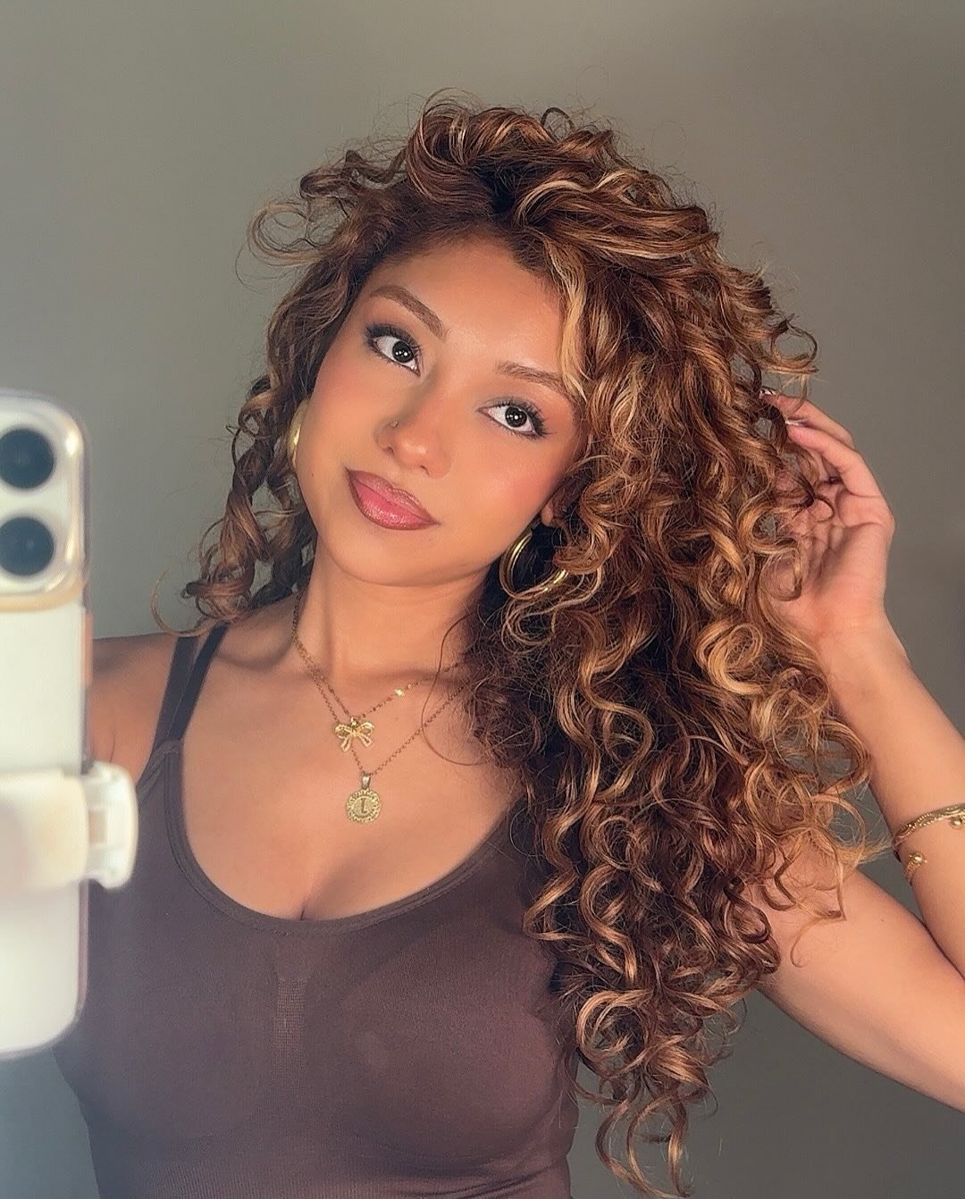 Mulher com cabelo cacheado volumoso e loiro, com expressão serena, usando acessórios. Ideal para o Guia do cabelo cacheado.