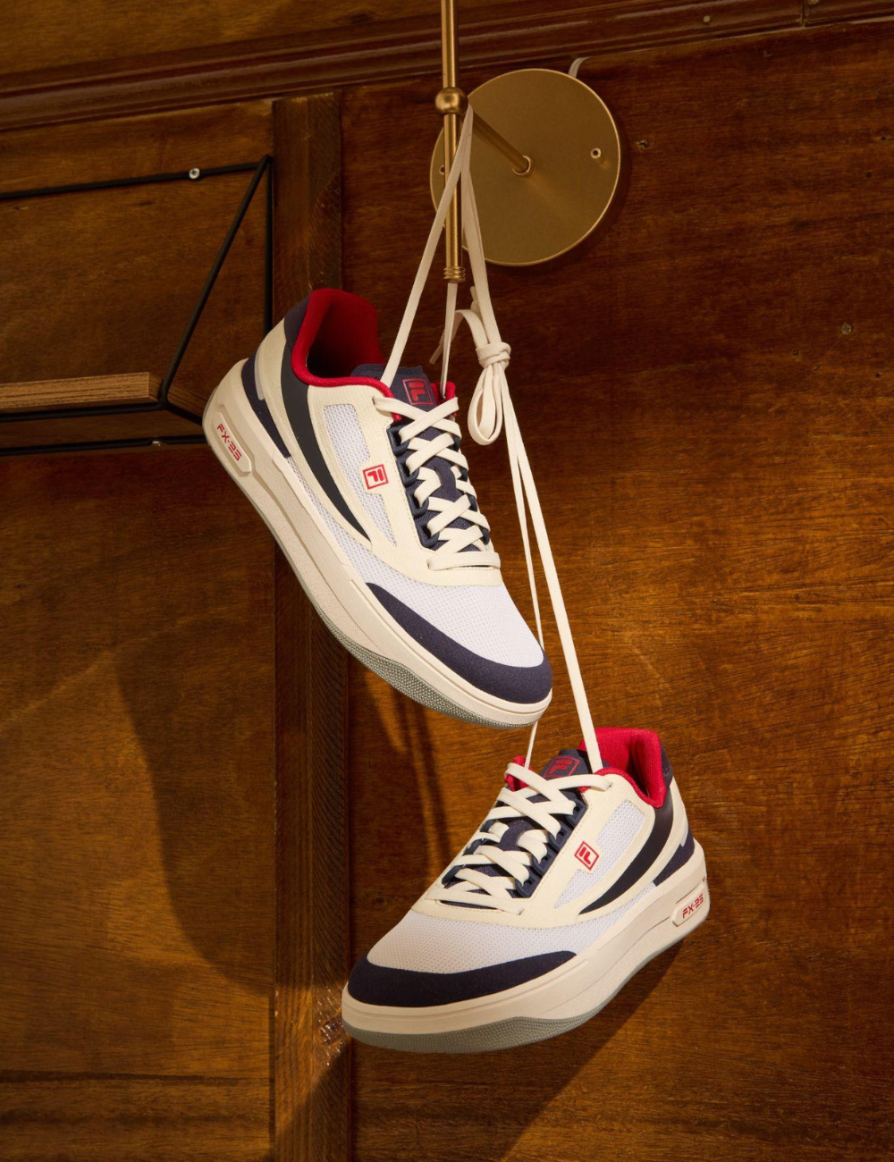 Tênis brancos com detalhes vermelhos e azuis pendurados, representando lançamentos de moda estilosos.