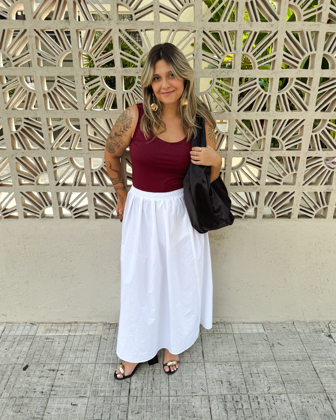 Look stealer usando saia branca, regata vinho, sandália de salto e bolsa preta - produção inspirada no estilo minimalista elegante