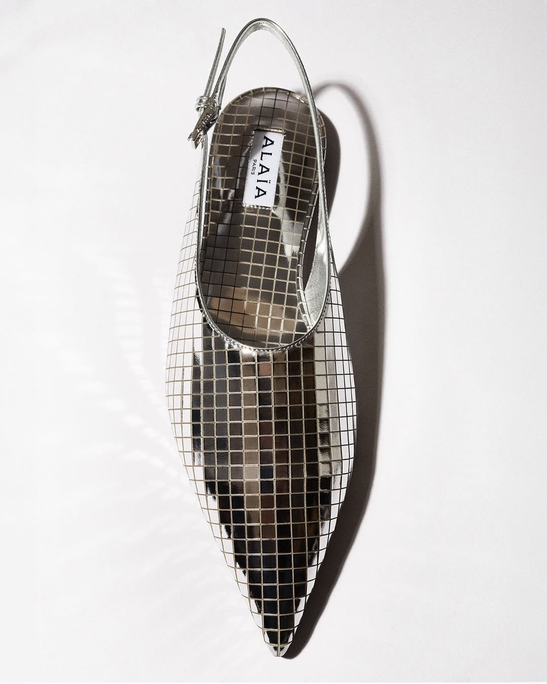 Slingback prateado com design quadriculado e detalhe refletindo a tendência loud luxury.