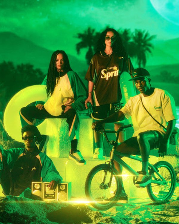 Grupo de pessoas posando com roupas da collab Approve e Sprite, ambientado em cenário verde iluminado por neon. Motociclista à direita.