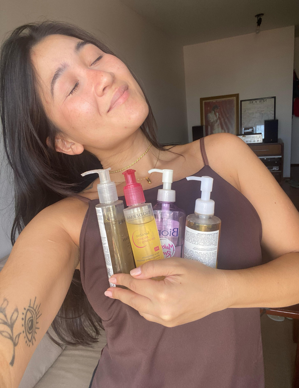 Pessoa sorrindo segura várias embalagens de óleos de limpeza facial.
