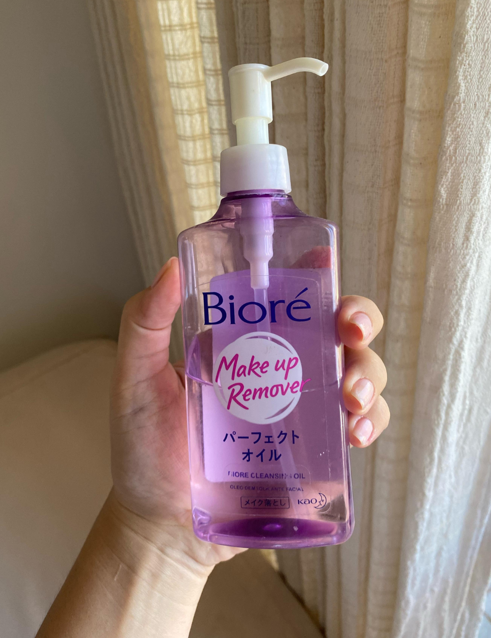 Garrafa de óleo removedor de maquiagem Bioré sendo segurada por uma mão. É um tipo de cleansing oil.