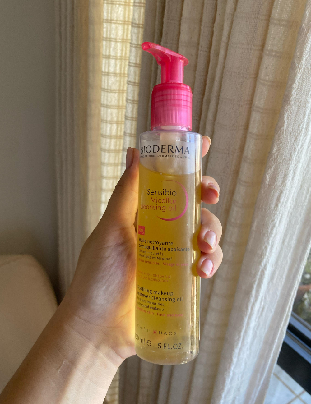 Bioderma Sensibio óleo micelar para limpeza de maquiagem, em embalagem com pump rosa, à luz natural.