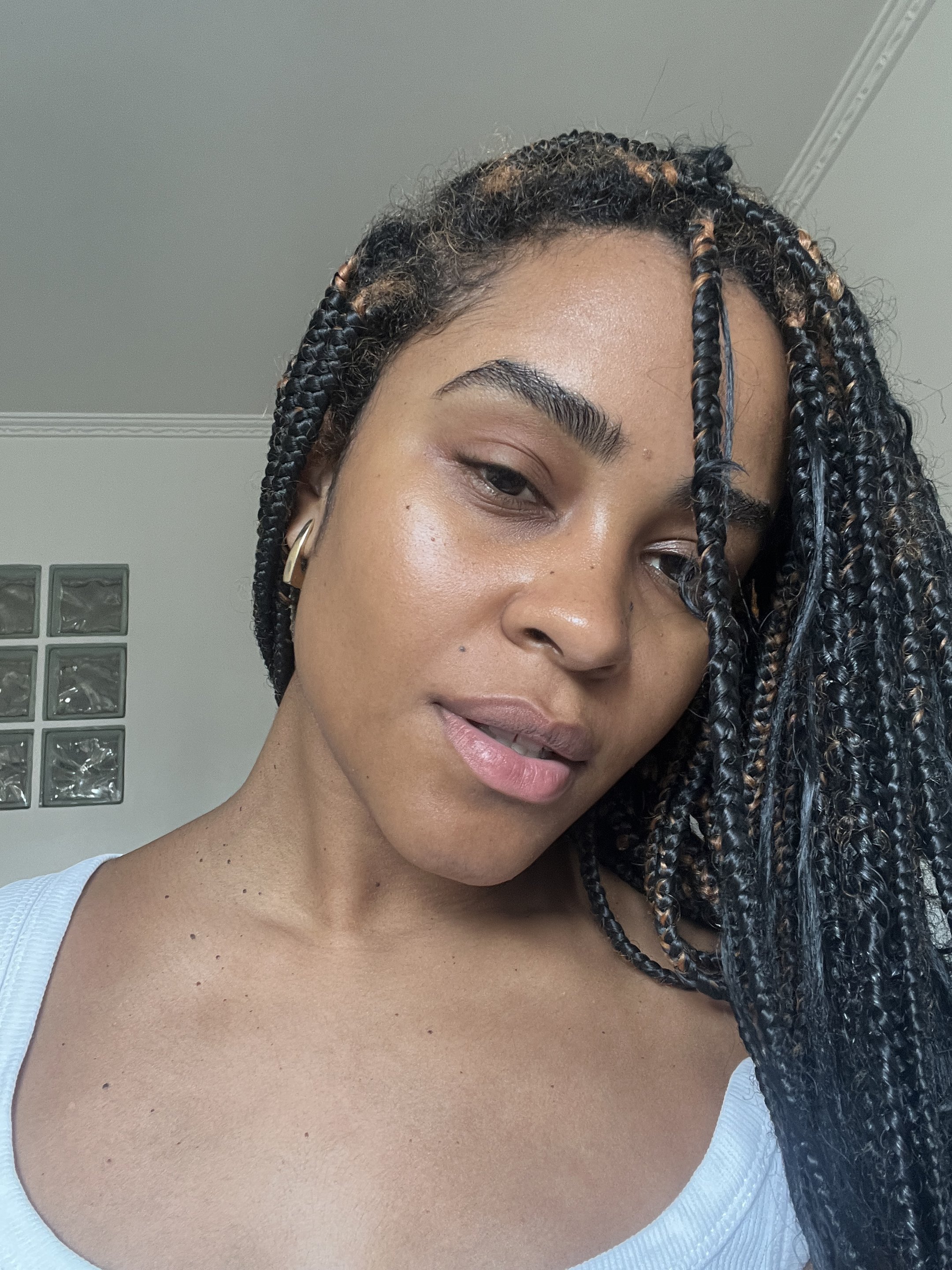 Rosto de uma mulher com tranças, pele luminosa. produtos da Glow Recipe aprimora a aparência com seus produtos.