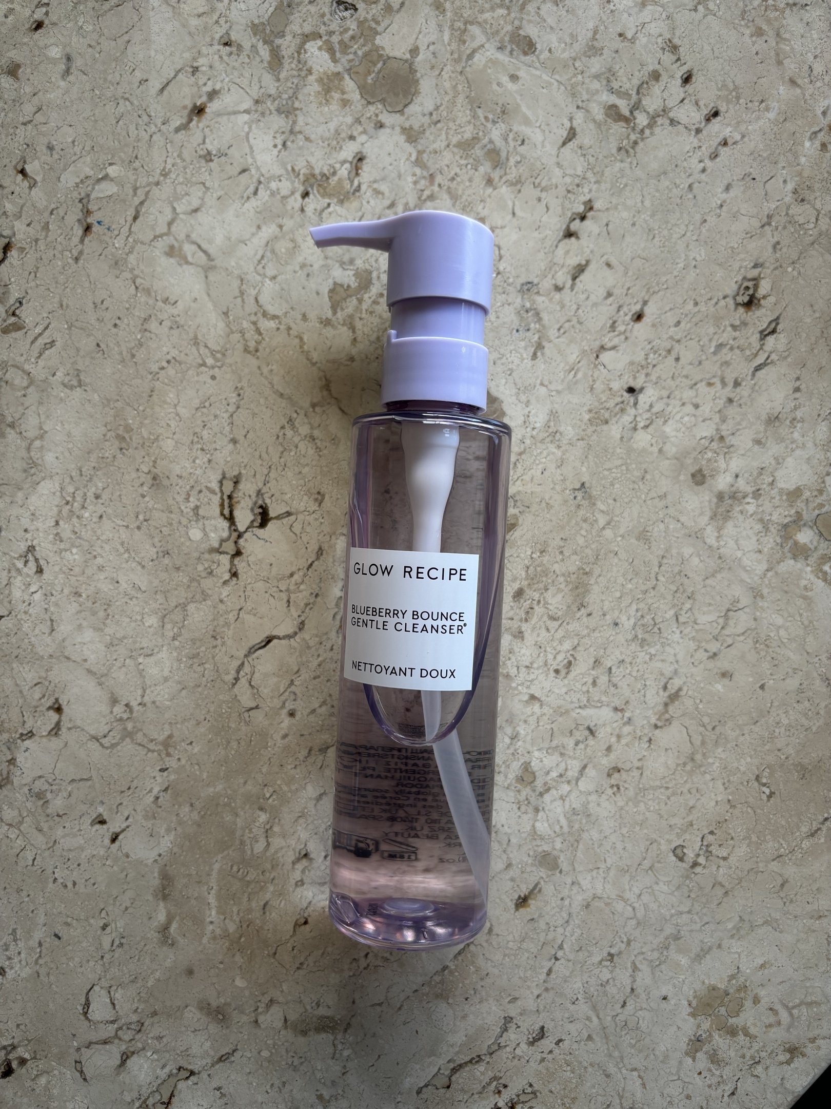 Embalagem de limpador facial Blueberry Bounce produtos da Glow Recipe com tampa roxa sobre fundo marmorizado.