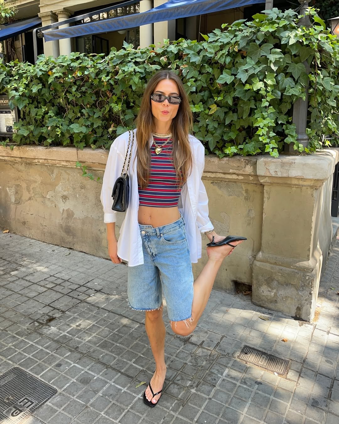 Influenciadora usa blusa listrada, camisa branca, chinelo preto e bermuda jeans oversized