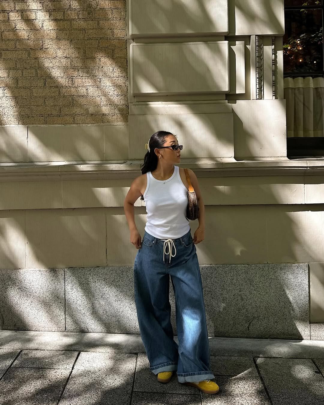 influenciadora usa camiseta branca, tênis amarelo e calça jeans oversized, a peça mais versátil