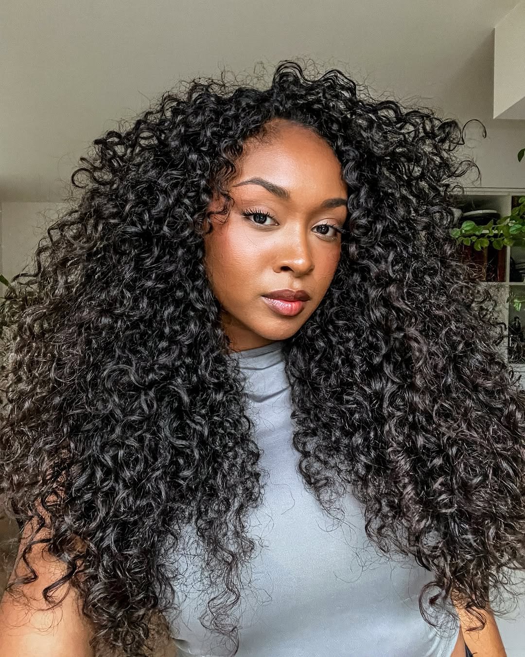 Mulher com cabelo cacheado e volumoso, destacando a beleza natural e inspirando cuidados do
