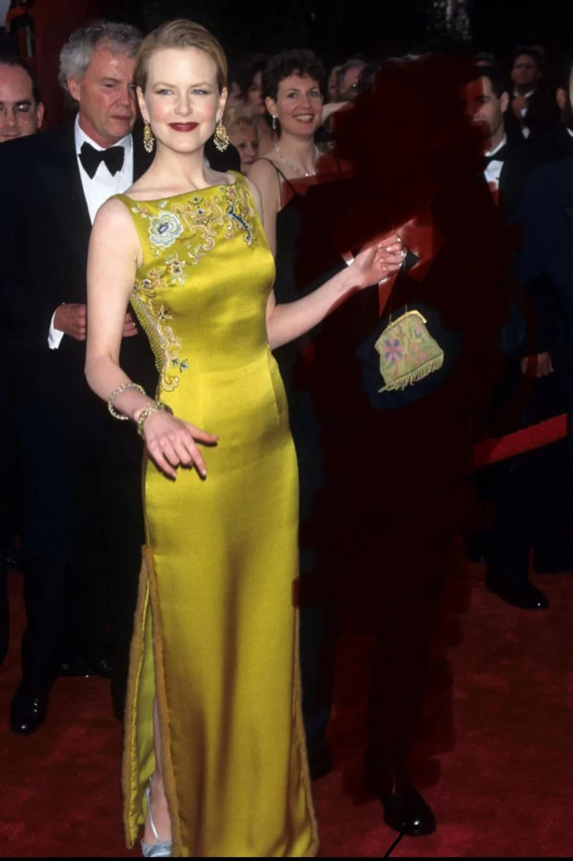 Vestido amarelo elegante em evento de tapete vermelho, adornado com bordados delicados e acessórios dourados.