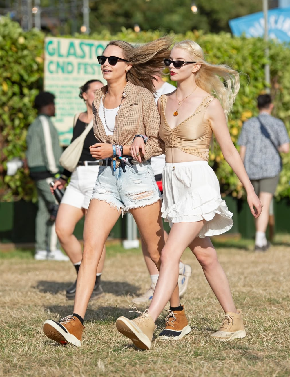Duas pessoas andando com looks inspirados em tendências vintage em um festival ao ar livre.