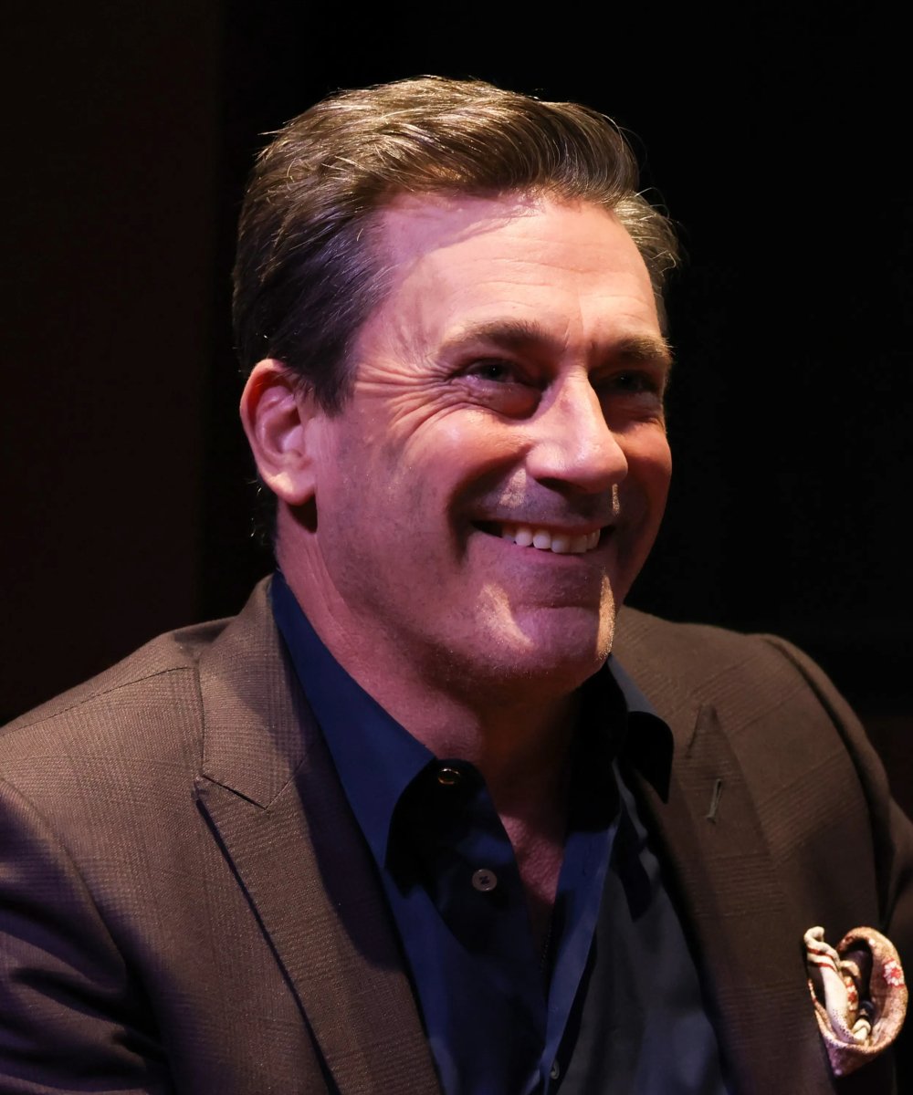 Uma pessoa sorrindo, vestindo terno escuro e camisa azul. Contexto de evento Sundance.