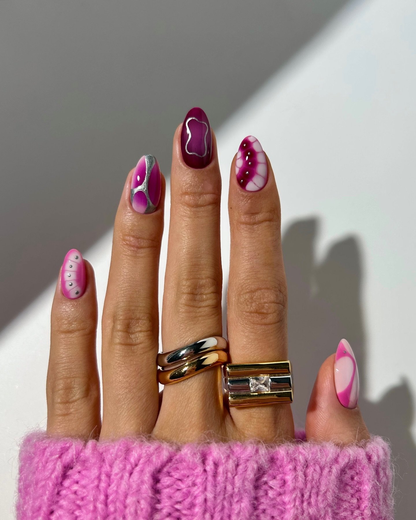 Unhas decoradas com padrão 3D em tons de rosa e roxo, usando esmalte brilhante.