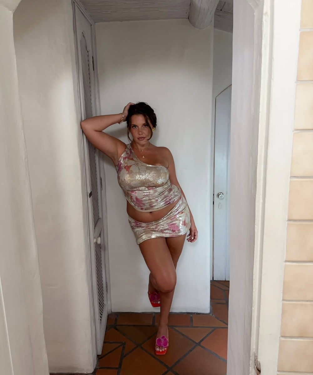 Pessoa posando em corredor de casa, vestindo conjunto brilhante, lembrando o estilo típico do verão em Ibiza.