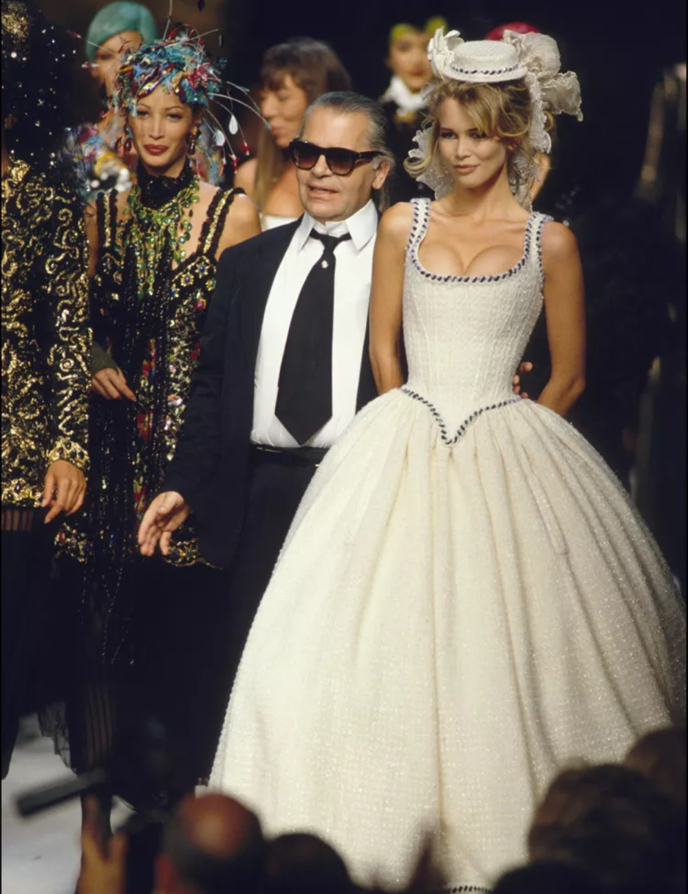 Desfile de moda com vestido de noiva da alta-costura, modelo elegante ao lado de um designer renomado.