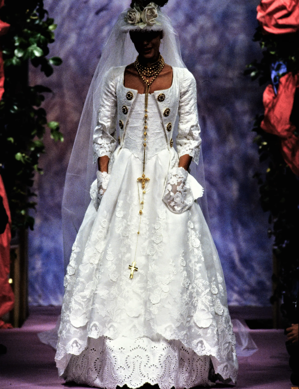 Desfile com vestido de noiva da alta-costura, renda elaborada, véu longo e colar dourado destacam-se.