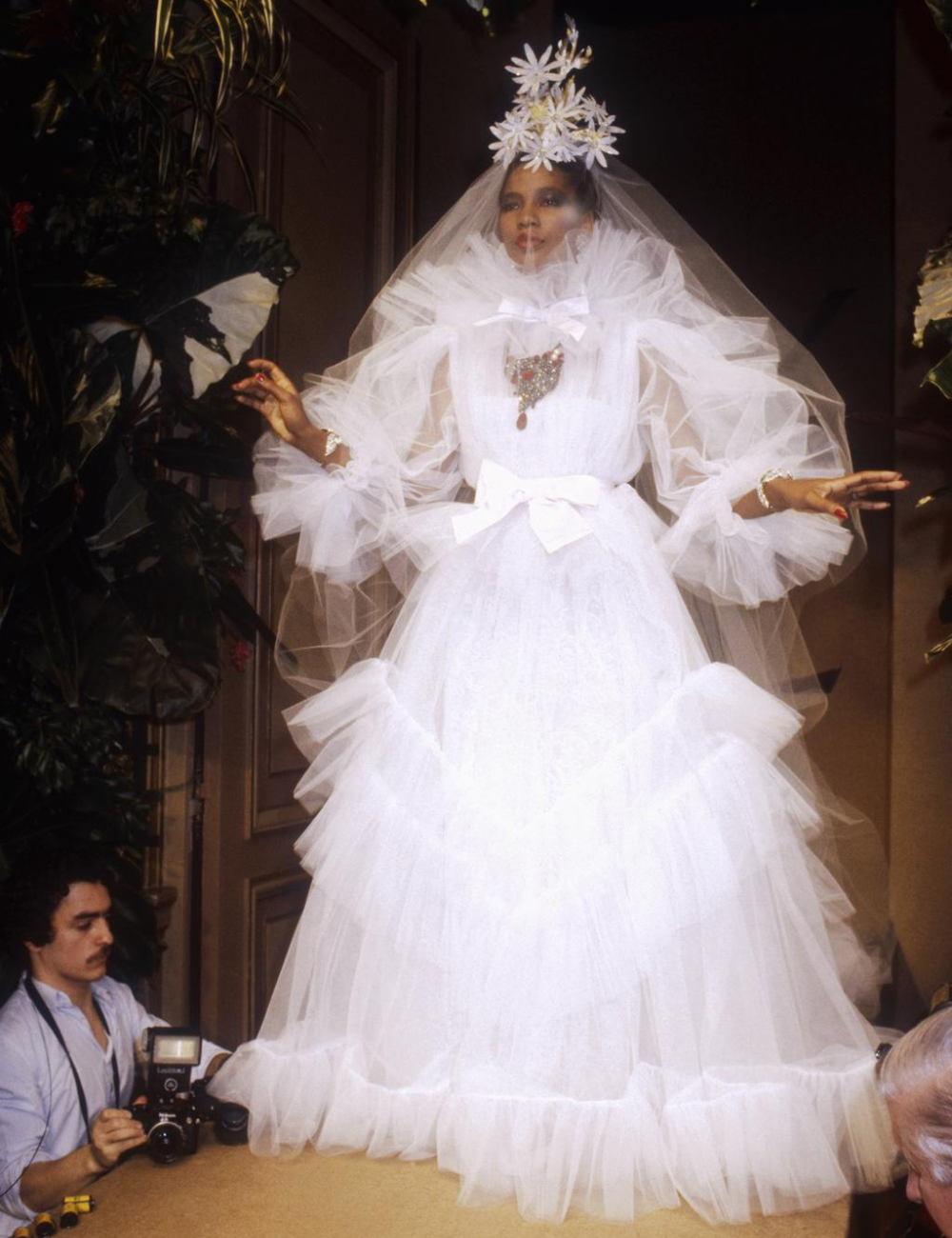 Vestido volumoso de noiva com véu e flores na cabeça, exemplificando alta-costura noiva. Fotógrafo capturando o momento.