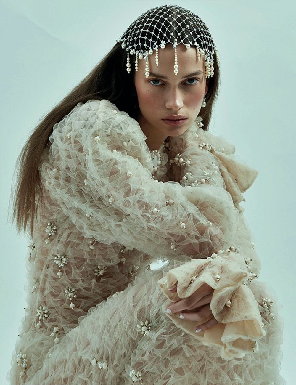 Vestido de renda com pérolas e acessórios de noiva em forma de rede no cabelo.