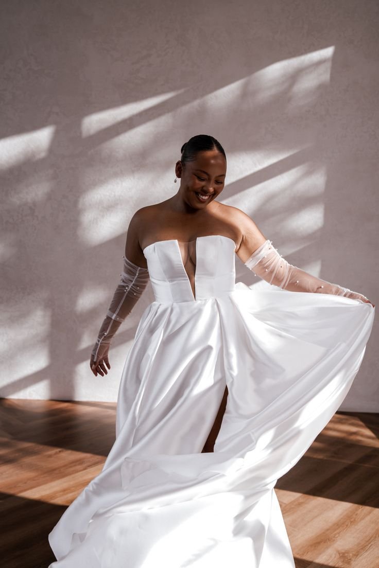 Noiva sorrindo em vestido elegante com tule nos braços, destacando acessórios de noiva complementares de casamento.