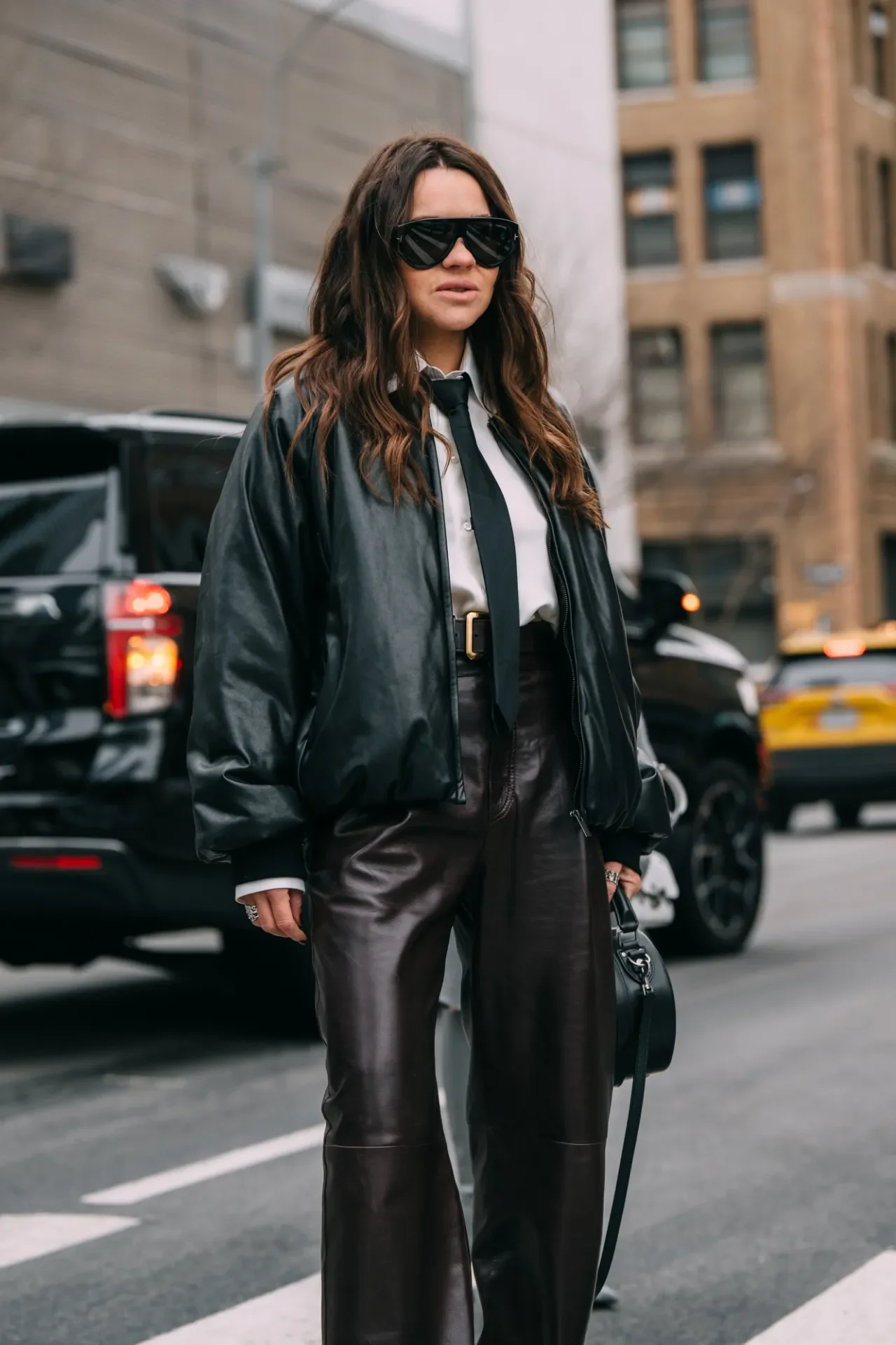 Mulher usando jaqueta e calça de couro em estilo urbano. Óculos escuros como acessório de moda.