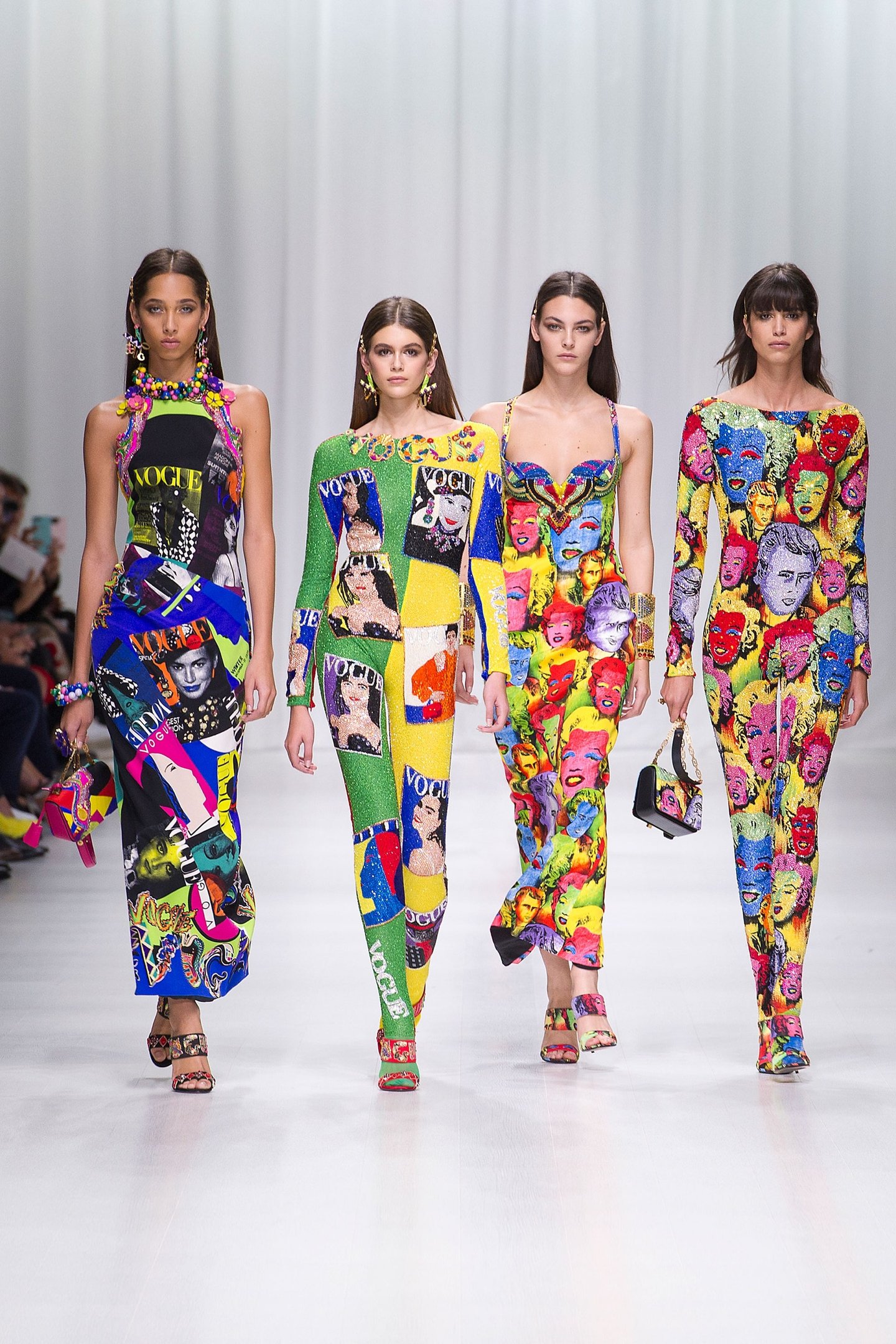 Modelos desfilam com vestidos coloridos e estampados de figuras icônicas, simbolizando a era pop, em coleção Versace.