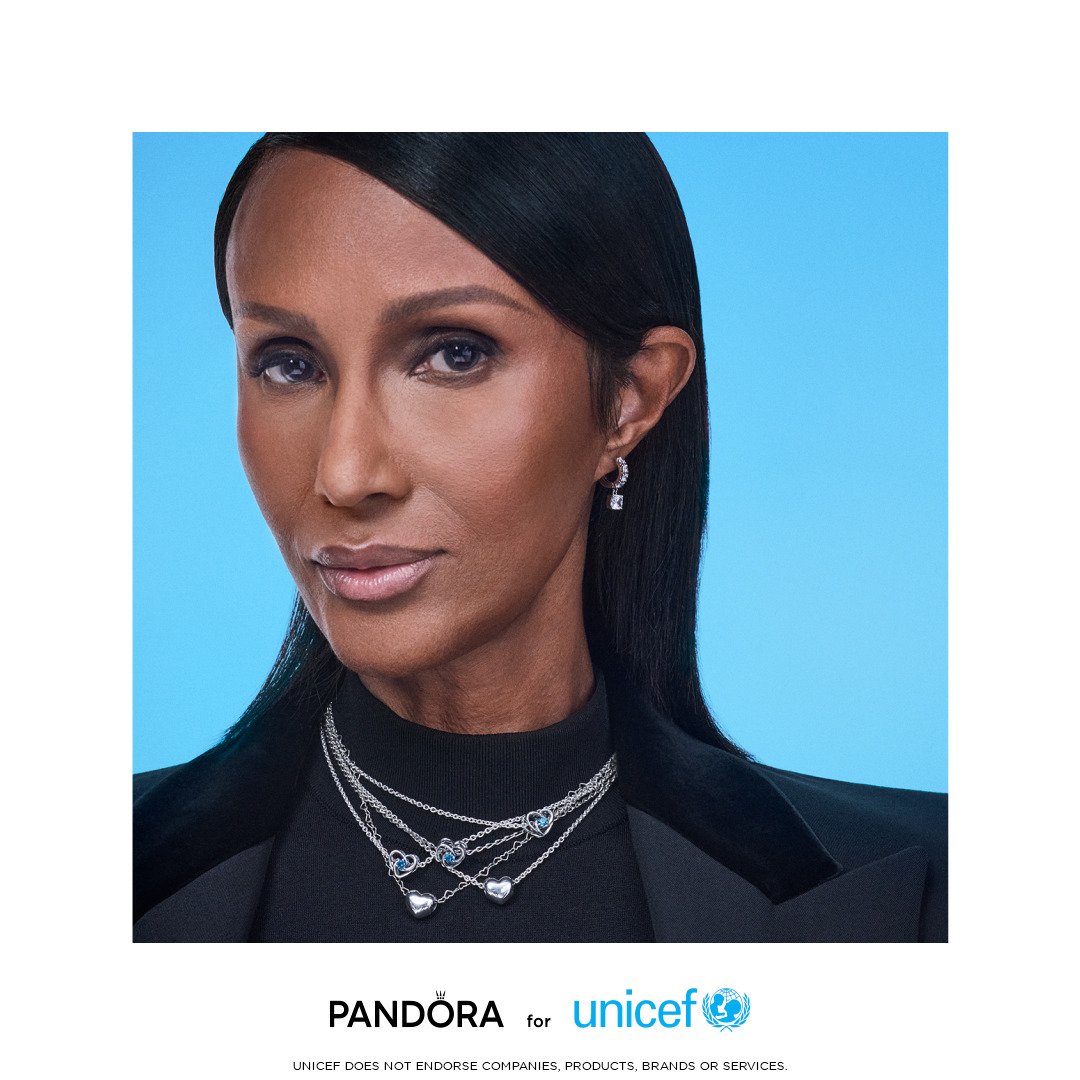 Pessoa com joias Pandora e UNICEF posando em campanha com fundo azul.