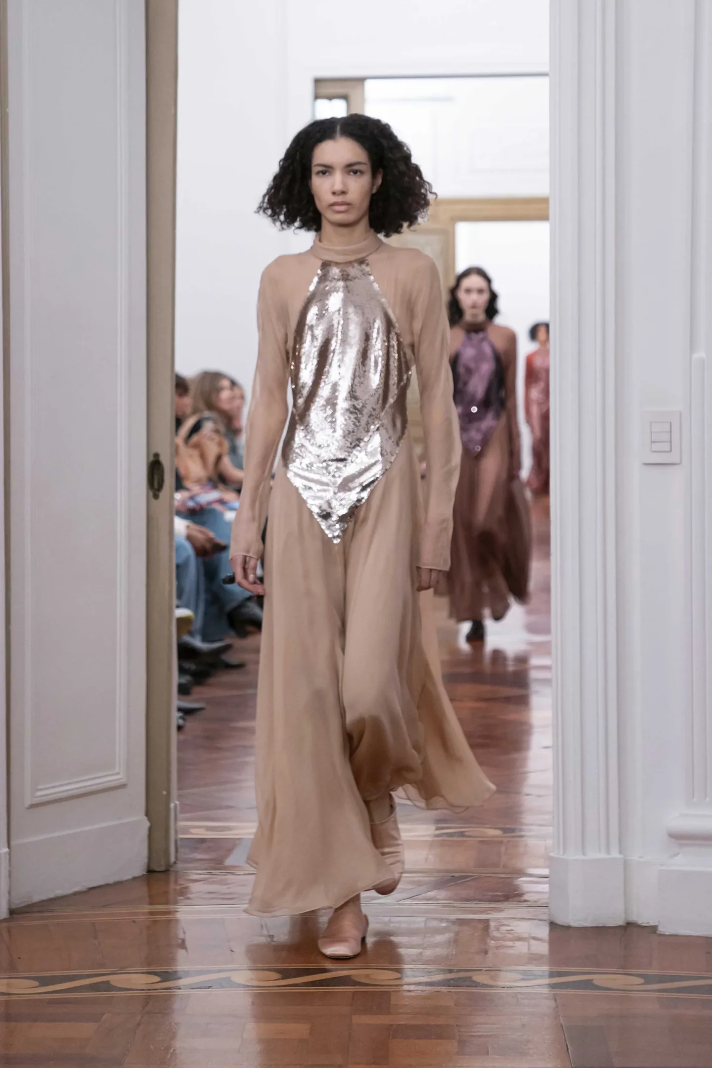 Modelo com vestido elegante em tons neutros e detalhes brilhantes desfilando em passarela. Medieval Core