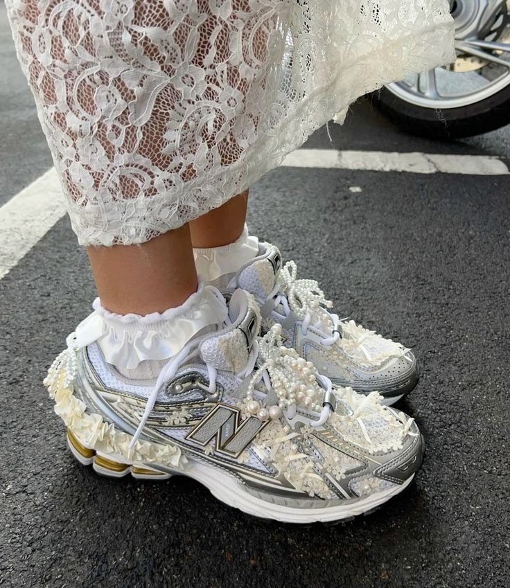 Tênis decorados com miçangas e rendas, combinados com meias de babados, sob uma saia de renda branca. Charms para tênis