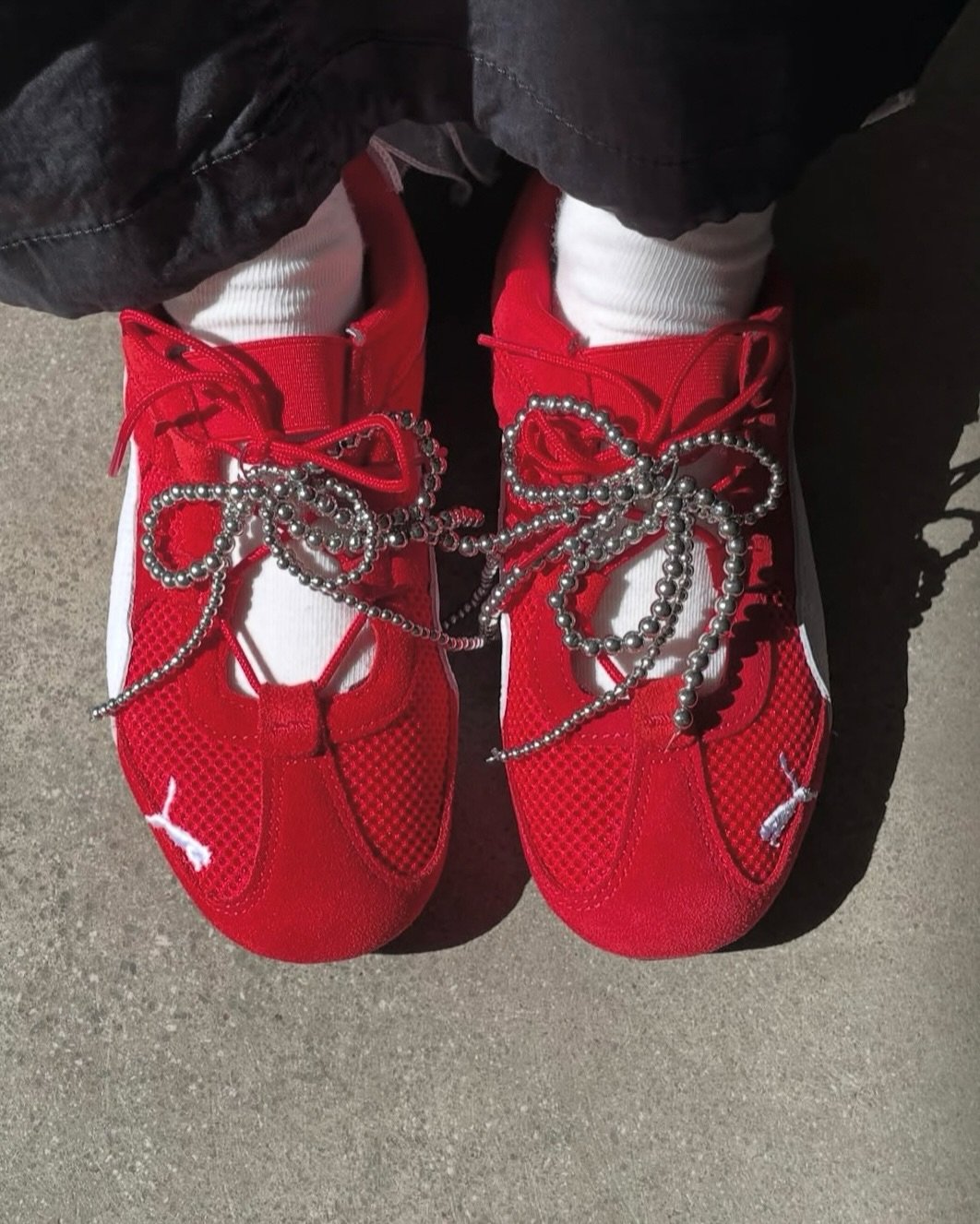 Tênis vermelhos com laços de bolinhas, combinados com meias brancas.